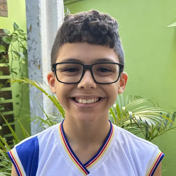 Luiz Guilherme, aluno do 5º ano do Colégio Vencer, sorrindo de óculos e uniforme